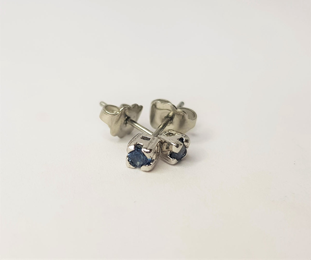 Pair of round blue sapphire claw-set sterling silver stud earrings with butterfly backs on a plain white background