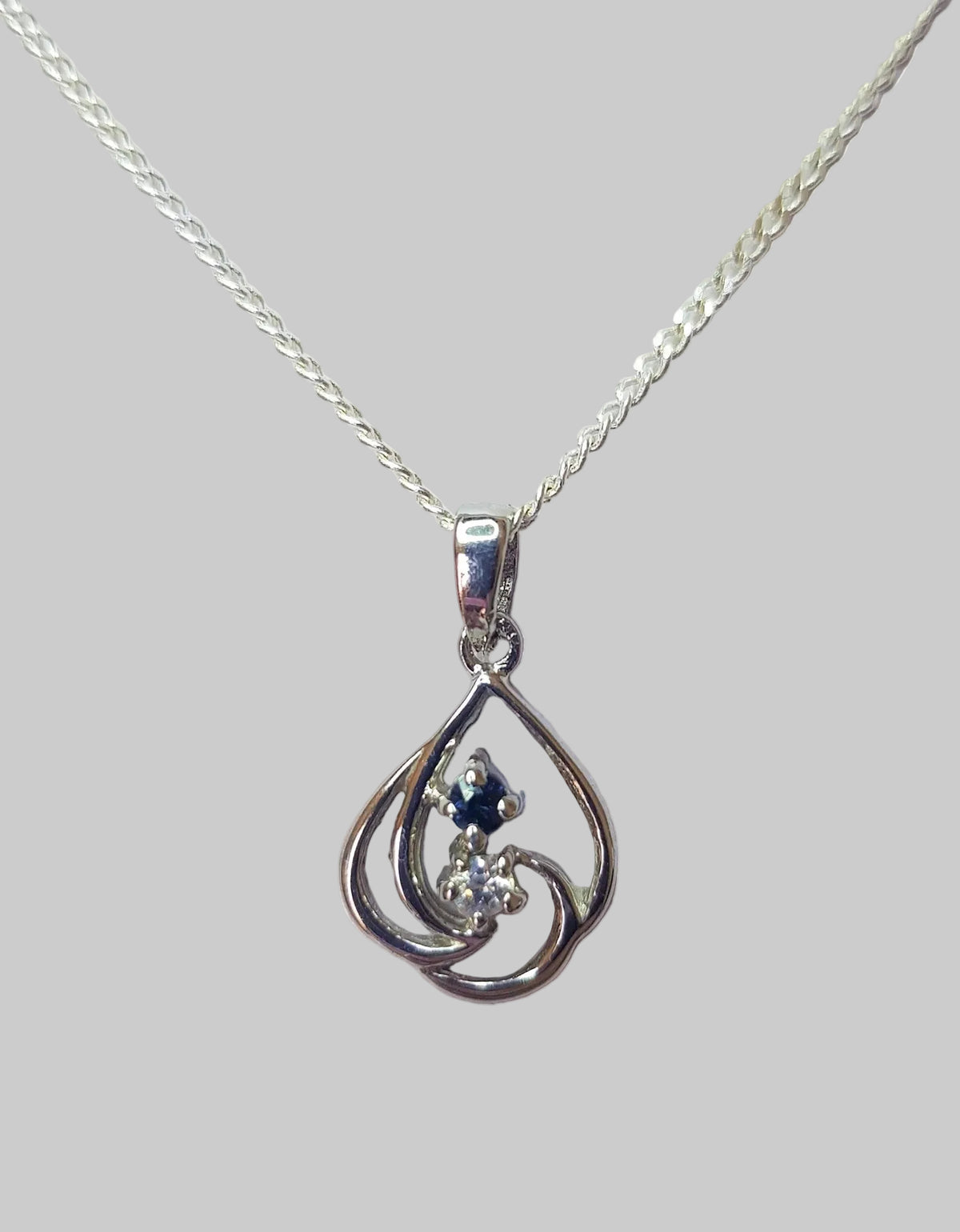 Sterling silver swirl pendant necklace featuring a sapphire and cubic zirconia on a chain against a white background