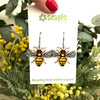 Bee-shaped earrings on a card with 'smyle' branding against a natural background