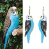 Realistic parakeet on a branch next to a pair of matching earrings with similar design