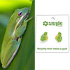 Green frog on a leaf with Smyle Designs earrings featuring frogs on a white background.