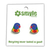 A pair of small colorful bird stud earrings on a white display card. The birds are multicolored with blue, green, yellow, and red feathers, and the card has the brand name 'smyle designs' printed at the top.