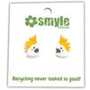 A pair of small coq hopster stud earrings on a white backing card. The earrings are white with bright yellow-orange spikes and a small black face.
