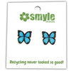 A pair of blue and black butterfly stud earrings displayed on a white backing card with the brand name 'smyle DESIGNS' and the slogan 'Recycling never looked so good!'.